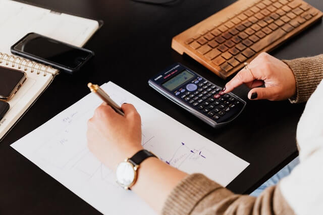 crop woman using calculator and taking notes on paper crop woman using calculator and taking notes on paper